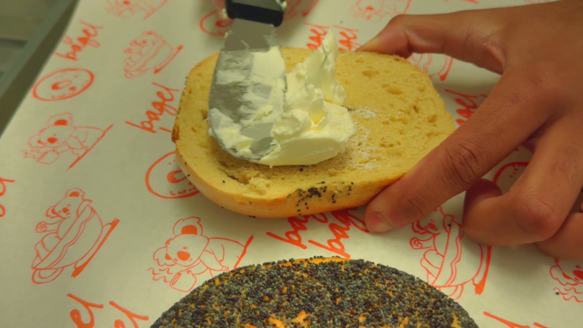 a bagel being schmeared on bagel bagel paper